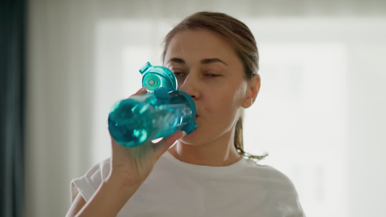 mujer atleta corre en una cinta de correr bebiendo agua de cerca. deportista trabaja en un club de fitness con ropa deportiva en cámara lenta. regímenes de fitness internos