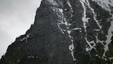 Tilt-up-camera-movement-showing-a-dark-steep-mountain-ridge-with-some-patches-of-snow-in-the-Bucegi-Carpathian-Mountains