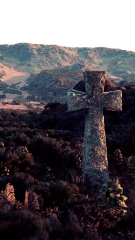 stone cross in a field with mountains in the background