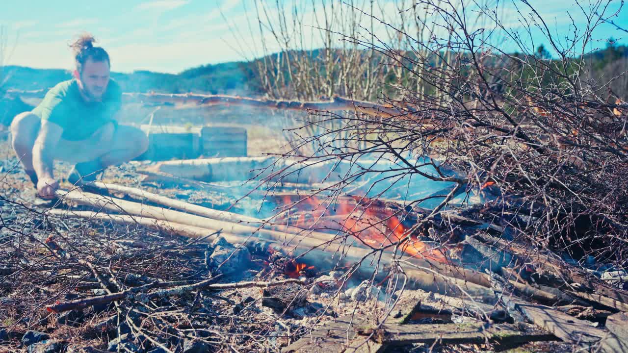 A Man is Turning the Poles to Carefully Burn Them to a Char - Close Up
