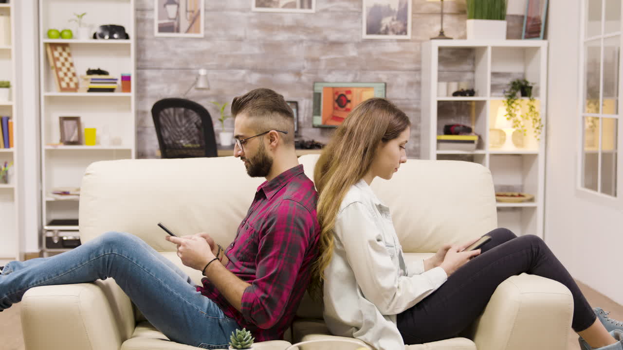 Couple on Couch Using Smartphones, Experiencing Relationship Problems