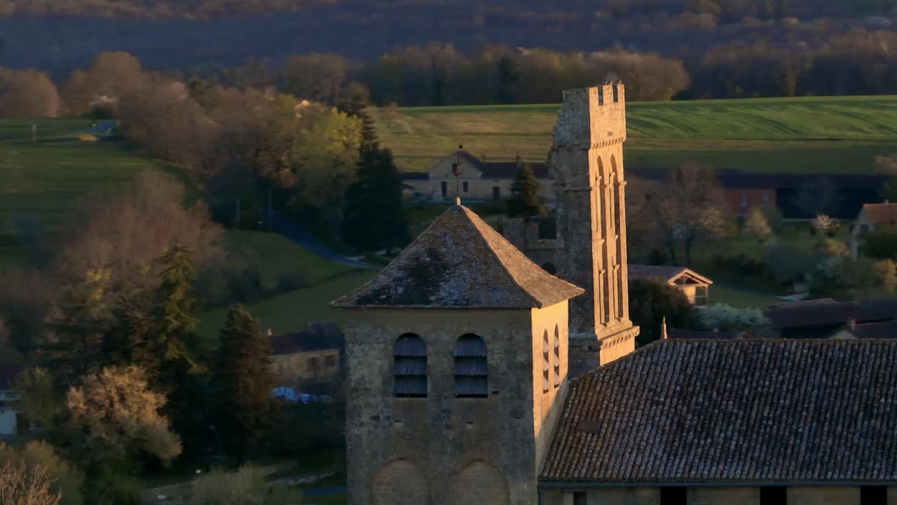 Aerial view of a church in France using a telephoto lens, drone shot of the steeple with a circular movement, pigeons flying around the steeple, Saint-Avit-S&eacute;nieur in the Dordogne