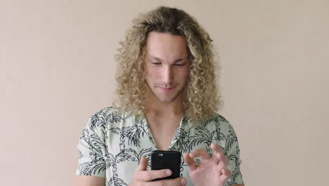 portrait of attractive young man smiling using smartphone browsing social media