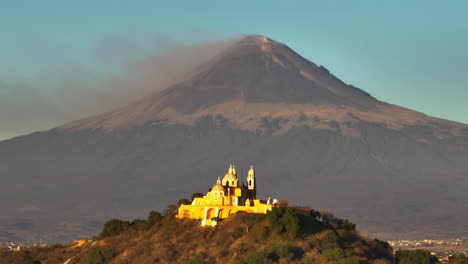 telephoto drone shot of the church on the cholula pyramid with popocatépetl volcano background