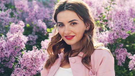 woman in a pink coat among lilacs