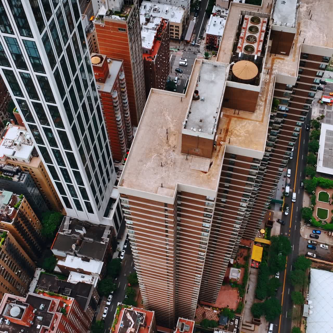 Lowering above the tops of high buildings at downtown. Numerous cars move by New York roads