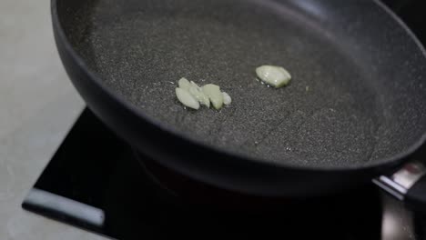 fried sliced garlic and boiling food oil in the black pan