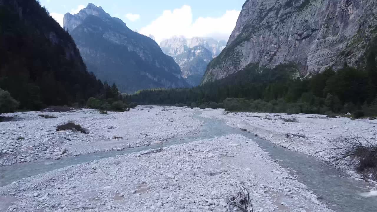 río casi seco con majestuoso horizonte alpino, vuelo aéreo rápido a baja altitud