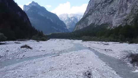 Almost-dry-river-with-majestic-Alps-horizon,-aerial-fast-fly-low-altitude