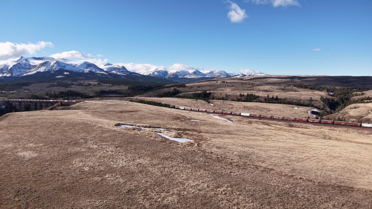 Vista aérea de pradera seca con parches de nieve y montañas distantes bajo un cielo azul claro en Montana.