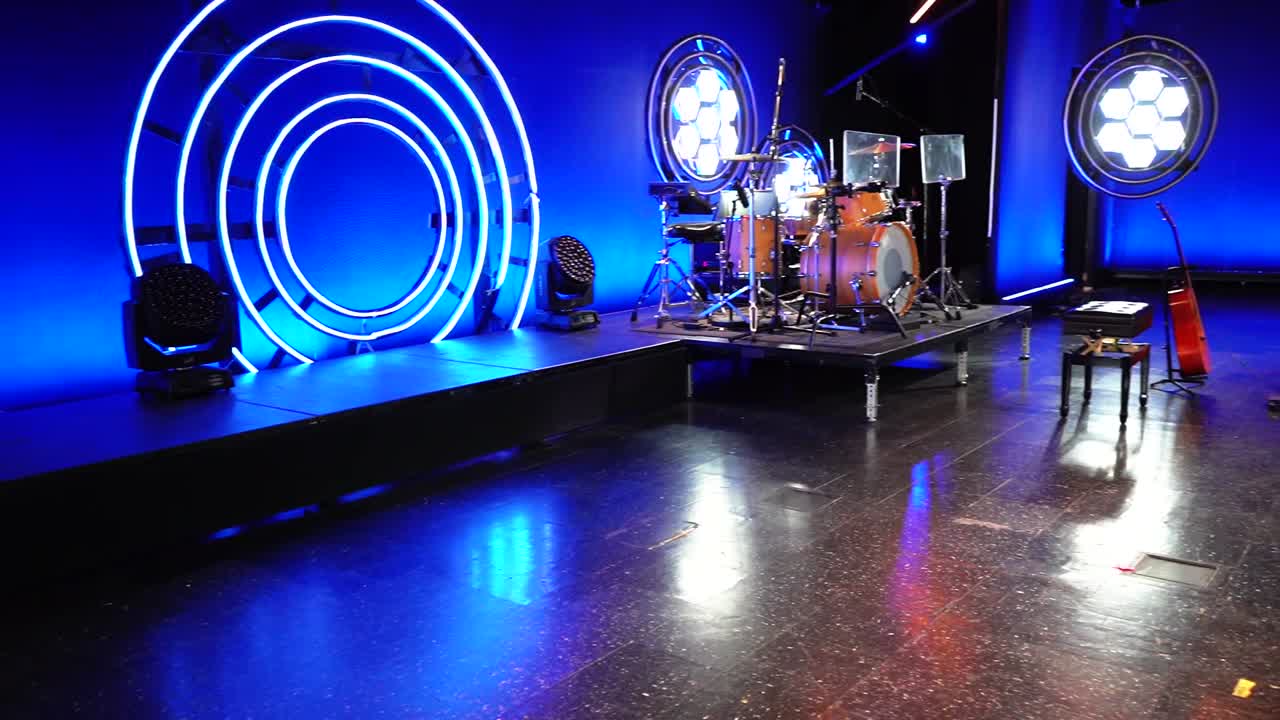 Drum set on stage with lighting in the background ready for concert.