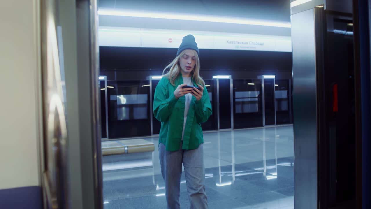 A young woman using her cell phone in a metro station
