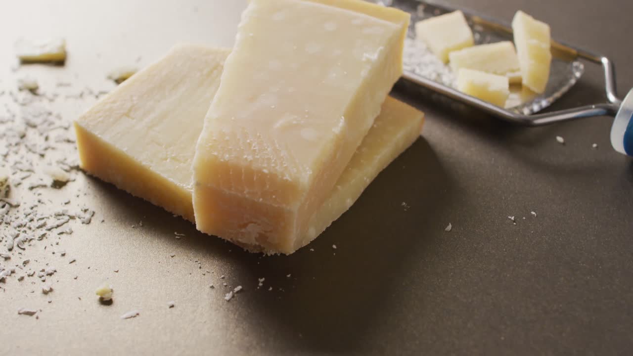 video de un bloque de queso parmesano y queso rallado queso en una mesa de madera