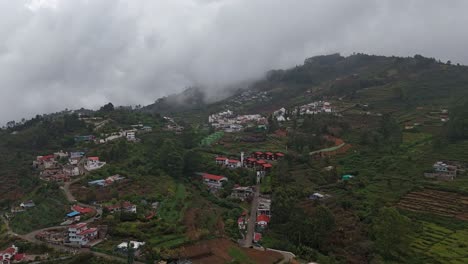 drone shot of white clouds gently covering the lush green hill slopes of kodaikanal