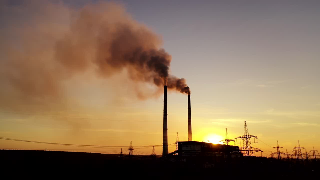 Evening background of industrial factory. Dirty smoke goes from pipes at sunset. Metallurgical plant with smoke on the evening sky.