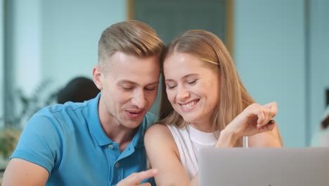 una pareja feliz hablando en el coworking. un tipo sonriente de cerca coqueteando con una chica rubia.