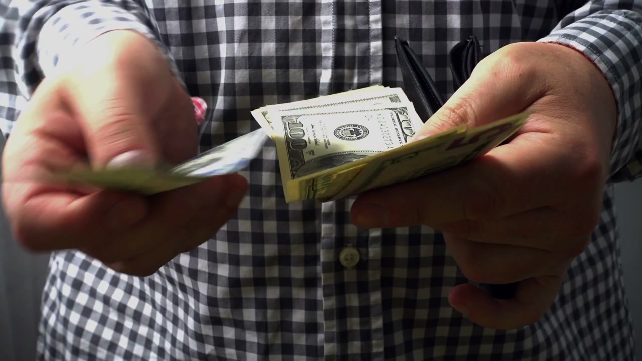 Un uomo ricalcola i dollari nel suo portafoglio