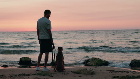 man and dog on a beach at sunset