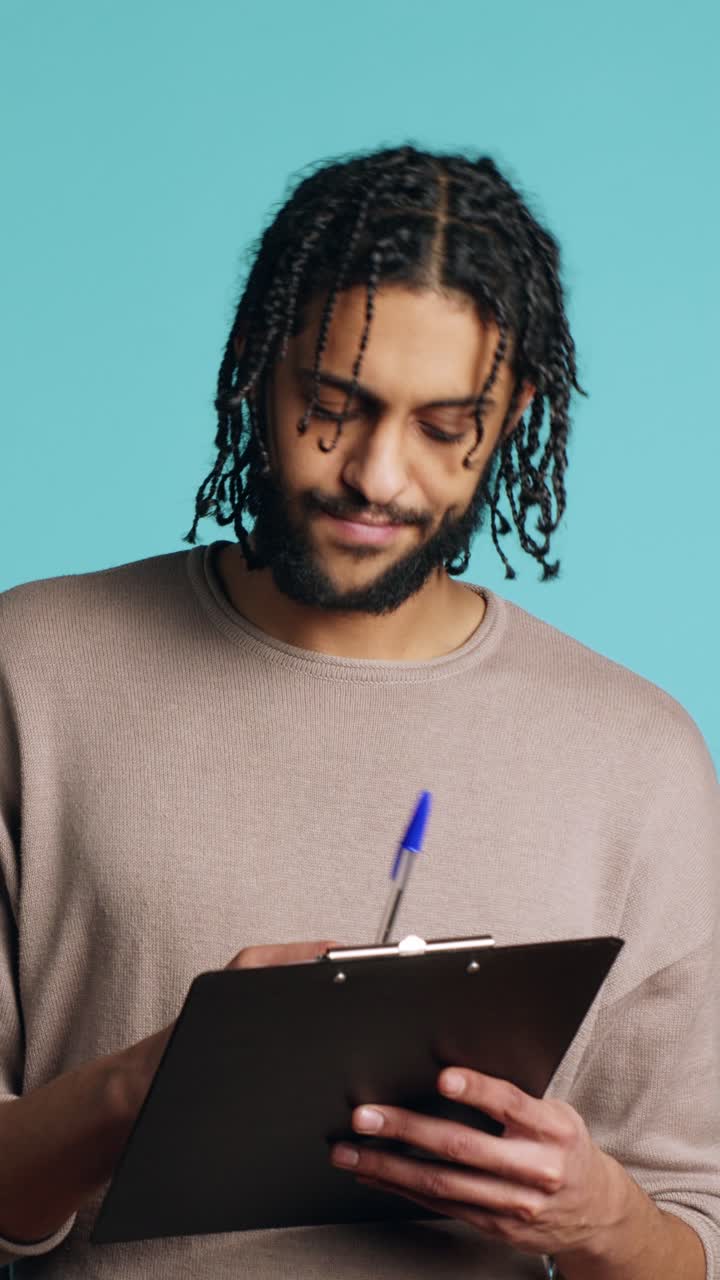 Video verticale. Uomo creativo che pensa a nuove idee, scrive su carta usando una penna, sfondo da studio