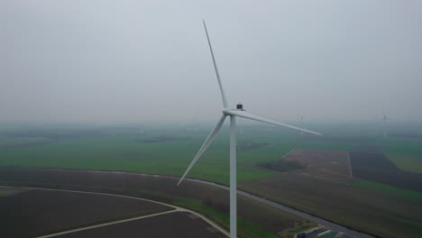 Several-wind-turbines-appear-as-the-drone-rotates-around-the-panorama-in-moody-weather
