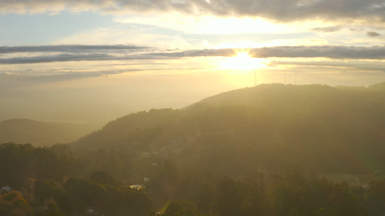 Vista aérea em ascensão paralela lenta da luz da tarde banhando a paisagem natural e torres de televisão no Monte Dandenong, Victoria, Austrália