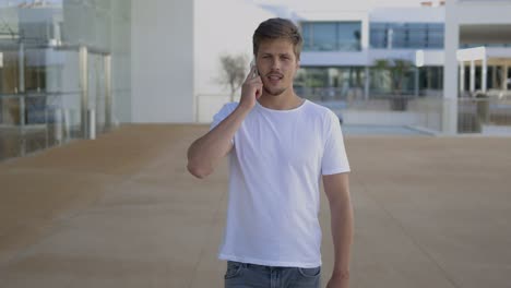 front view of focused young man talking on smartphone.