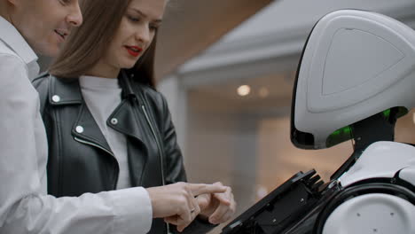 the couple communicates with robot assistant with information screen in duty to give information. contact with the robot and interaction with help systems.