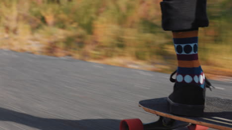 young friends feet longboarding together riding downhill skating fast using skateboard on countryside road happy teenagers enjoying cruising outdoors