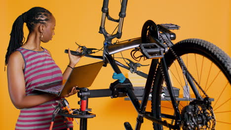 ingeniero hace mantenimiento de bicicletas, mirando la lista de mantenimiento de portátiles, fondo de estudio