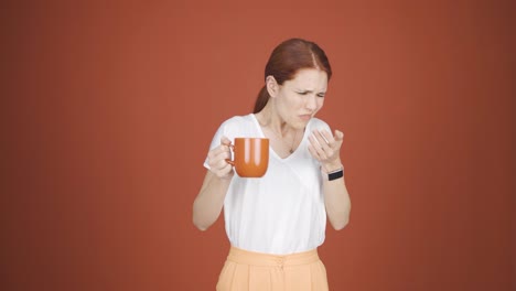 The woman&#039;s mouth is burning from the hot drink.