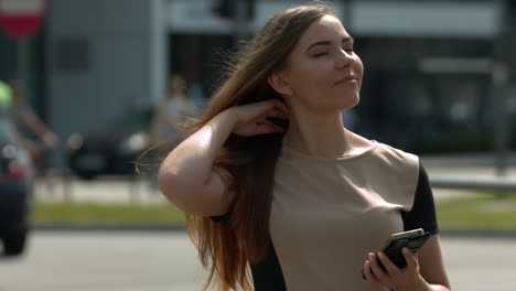 close up of a young girl in brown and black top in a big city on her phone updating social media
