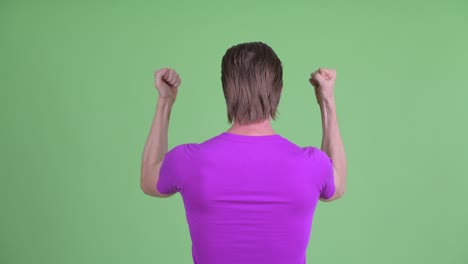fotografía de estudio de un joven con los brazos levantados contra un fondo verde