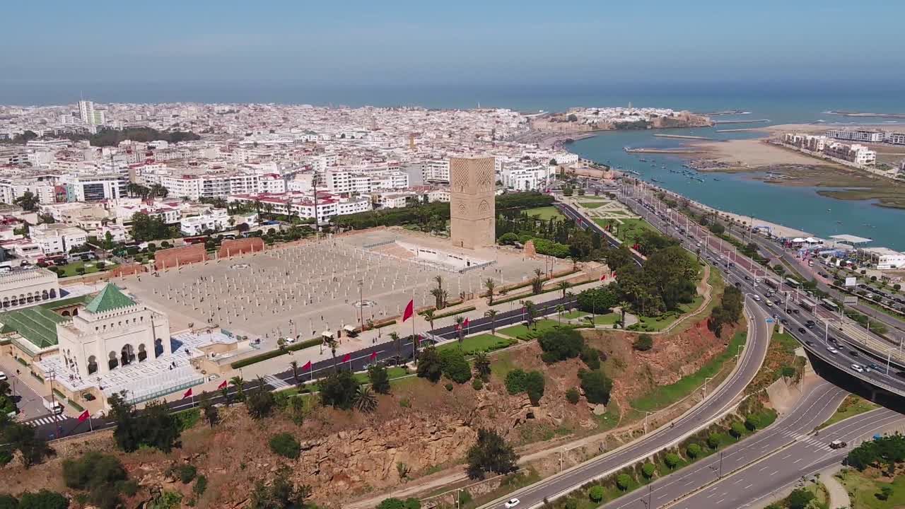 Panoramisk droneoptagelse af det historiske Hassan Tårn og Mausoleum for V. Viser de antikke søjler, mausoleet med grønt tag og floden Bou Regreg som baggrund i Rabat