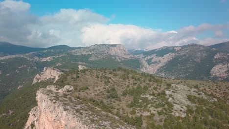 Reveal-shot-of-a-cliff-and-in-the-background,-mountains