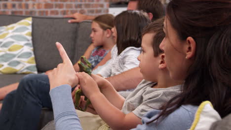 familia sentada en el sofá en una sala de estar abierta viendo televisión