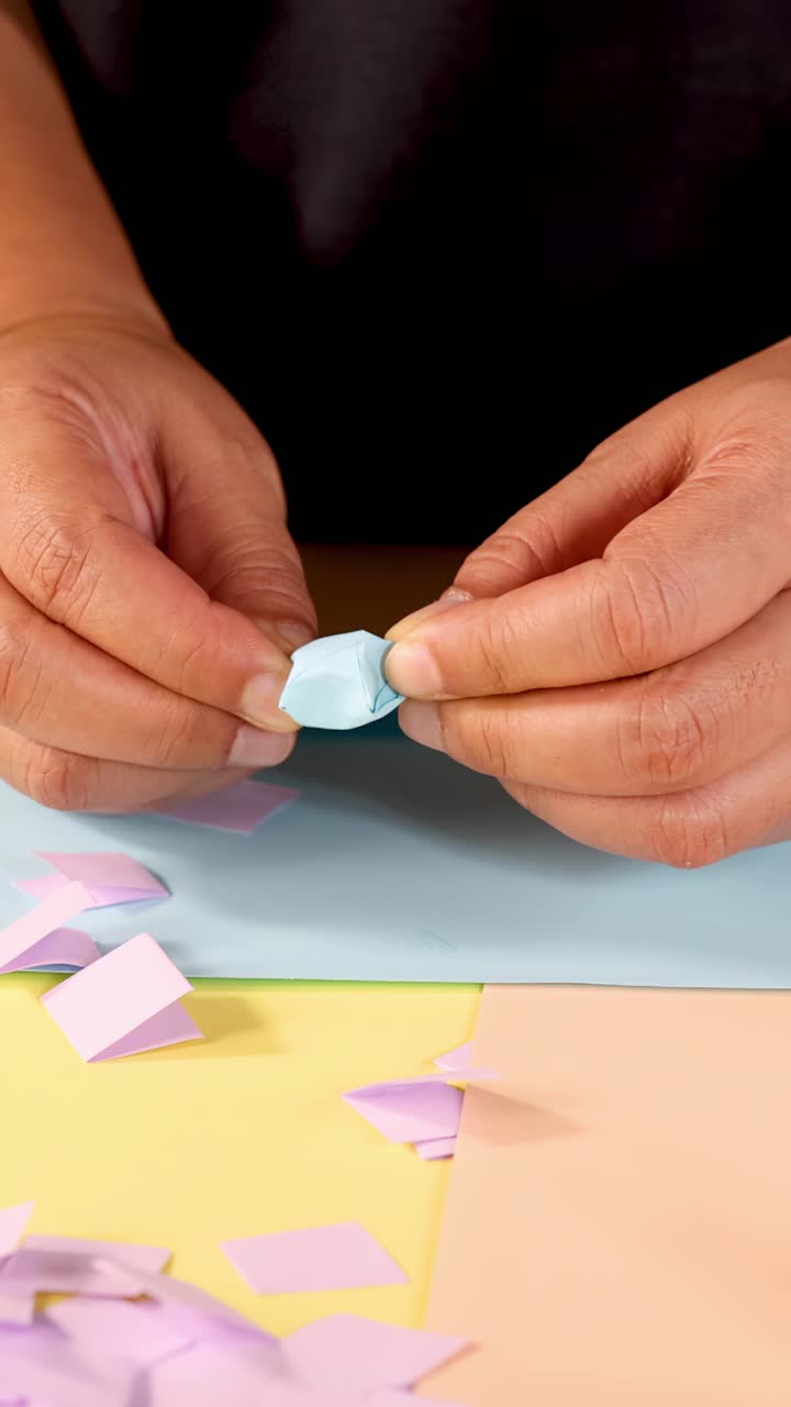Persona piega abilmente carta pastello in una stella di origami su un tavolo colorato, primo piano, illuminazione soffusa.