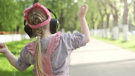 happy little girl wearing wireless headphones, listening to music and smiling.