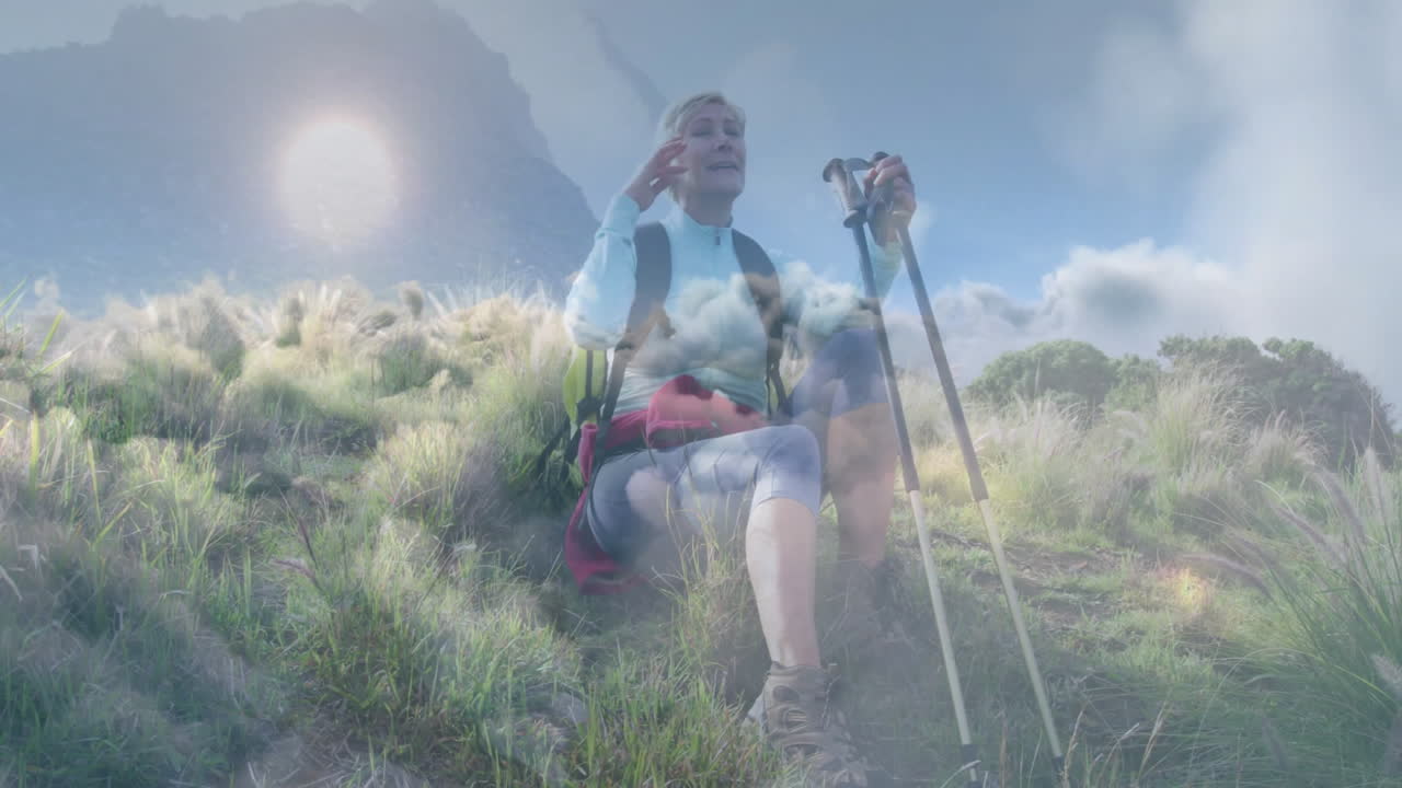 woman holding trekking poles on grassy mountain in health marketing, showing sun and cloud overlays
