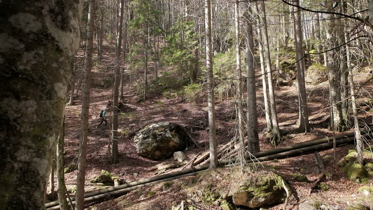 Sidestillingsbillede af vandreren, iført en lys blå trøje, der går fra venstre mod højre på en grusvej med en rygsæk.