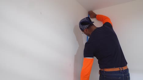 painter using masking blue tape to secure edges of wall - close up