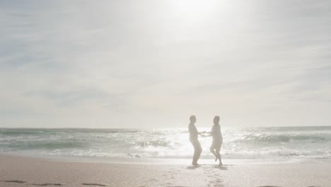 Glückliches-Hispanisches-Seniorenpaar,-Das-Bei-Sonnenuntergang-Am-Strand-Tanzt