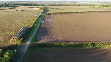 Aerial-footage-flying-over-tracked-farmer's-fields-and-hedgerows-along-side-a-narrow-lane-in-North-Yorkshire,-UK-on-a-beautiful,-sunny-autumn-morning