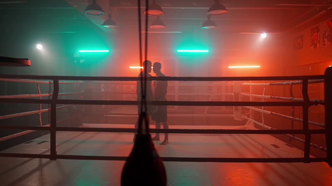 Boxer stehen sich in einem stimmungsvollen, neonbeleuchteten Ring gegenüber