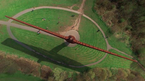 drone orbitando arriba, acercándose hacia la famosa escultura del ángel del norte en gateshead, reino unido, con gente en el suelo