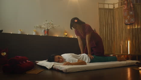 asian woman performs traditional thai massage to beautiful european woman. rehabilitation and treatment after injuries with the help of massage. relax and rest from massage of legs arms and back. therapeutic massage