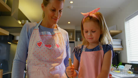 Front-view-of-young-Caucasian-mother-and-daughter-preparing-dough-in-a-bowl-4k