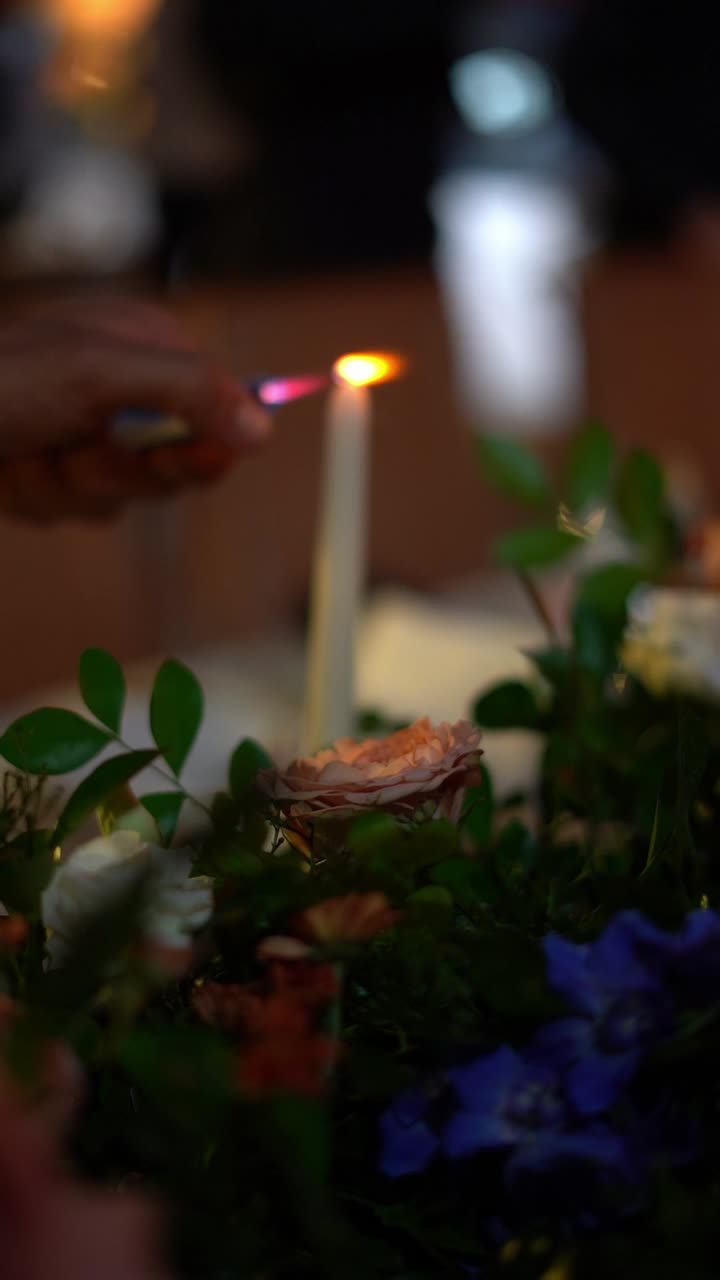 Un serveur allume une bougie blanche avec une allumette lors d'un dîner romantique, plan rapproché, plan d'insertion