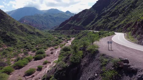 Antena-De-Montaña-Sigue-La-Carretera-A-Lo-Largo-Del-Lecho-Seco-Del-Río,-Naturaleza-Argentina