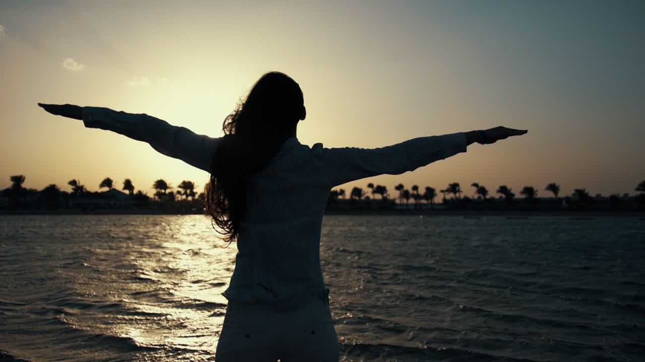 una mujer feliz abriendo los brazos hacia el atardecer. una chica bonita disfrutando del verano en la playa.