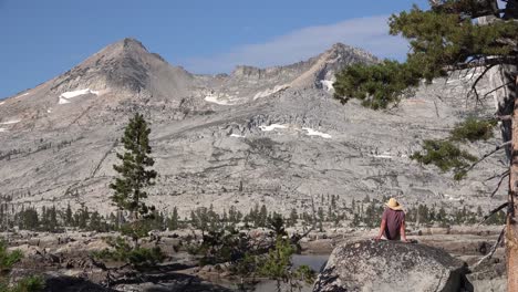 un hombre se sienta en una roca con vistas a la desolación del desierto en las montañas de sierra nevada california